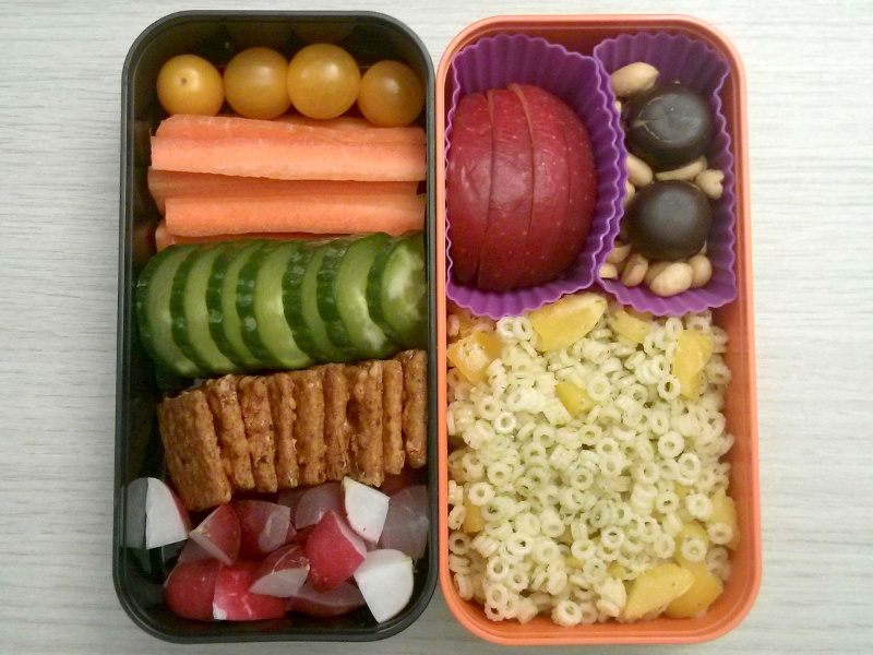 Bento Box gefüllt mit Tomaten, Möhren, Gurke, Cracker, Radieschen, Apfel, Studentenfutter, Schaumküsse, Nudeln