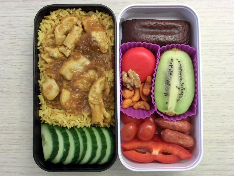 Bento Box gefüllt mit Cabanossi, Paprika, Tomate, Reis, Kiwi, Babybel, Nüsse, Schokokuchen, Geflügel, Gurke
