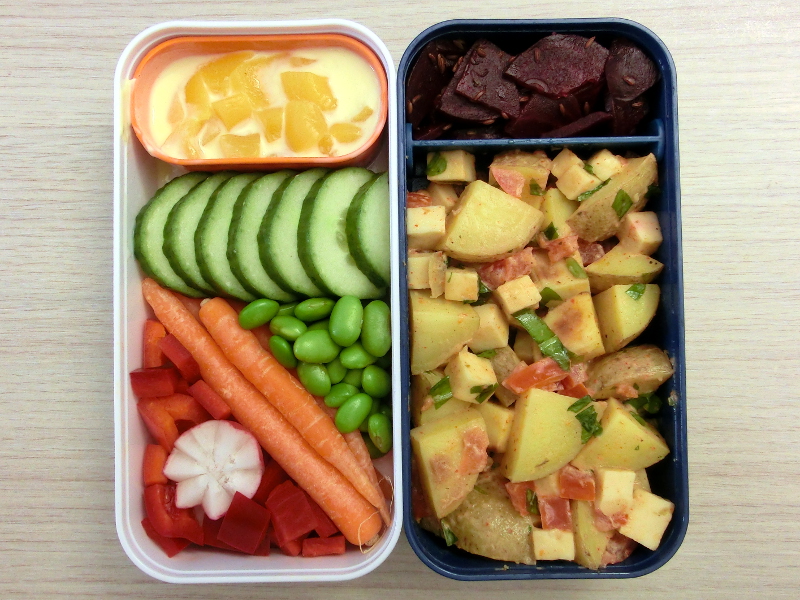 Bento Box gefüllt mit Möhren, Paprika, Gurke, Sojabohnen, Joghurt, Rote Beete, Kartoffelsalat