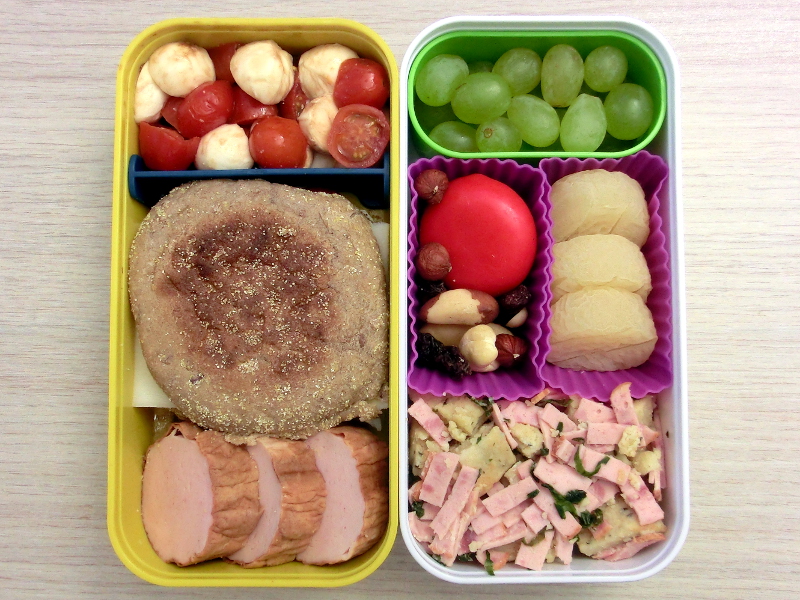 Bento Box gefüllt mit Brötchen, Leberkäse, Tomaten, Mozzarella, Weintrauben, Babybel, Studentenfutter, Harzer Roller, Knödelsalat