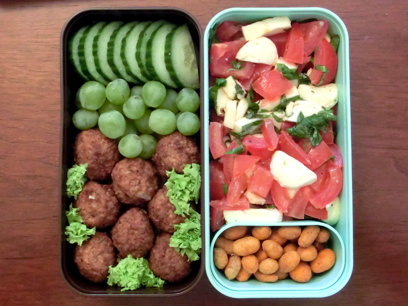 Bento Box gefüllt mit Tomate-Mozzarella Salat, Erdnüsse, Gurke, Weintrauben, Hackbällchen