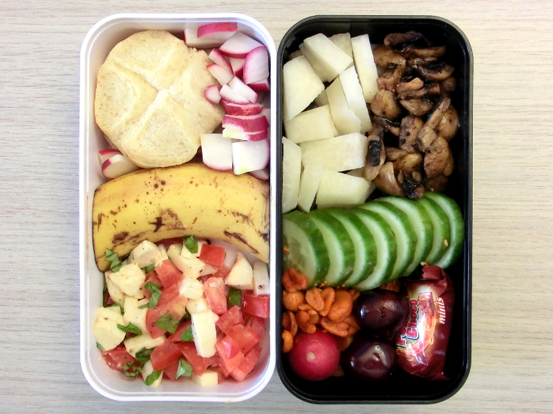 Bento Box gefüllt mit Brötchen, Radieschen, Banane, Tomate-Morzarella, Kolrabi, Pilze, Gurke, Erdnüsse, Kirschen, Schokolade