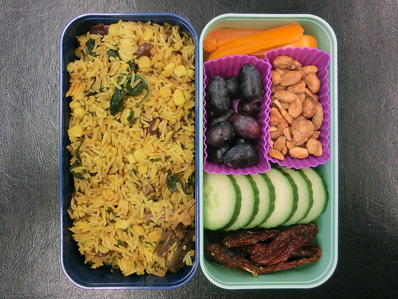 Bento Box gefüllt mit Andalusische Reispfanne mit Leber, Paprika, Weintrauben, Erdnüsse, Gurke, Getrocknete Tomaten