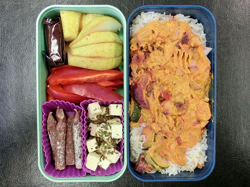 Bento Box gefüllt mit Reis mit Kürbissoße, Birne Schokolade, Paprika, Schafskäse, Würstchen