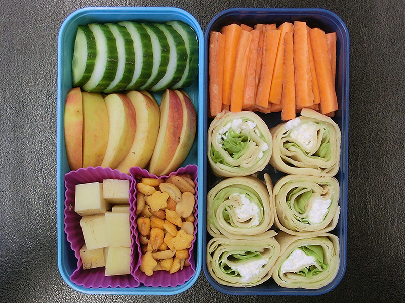 Bento Box gefüllt mit Gurke, Apfel, Käse, Nüsse, Karotten, Wraps