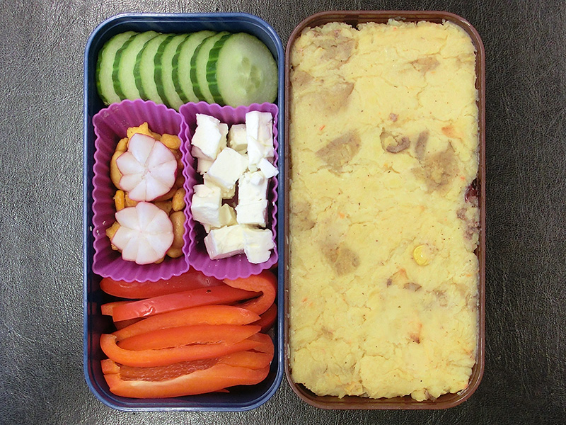Bento Box gefüllt mit Kartoffelmuss, Gurke, Radieschen, Schafskäse, Nüsse, Paprika